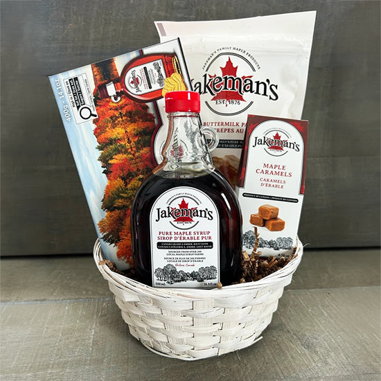 Gift basket with Jakeman's bottle, caramel snacks, and wrapped bag items