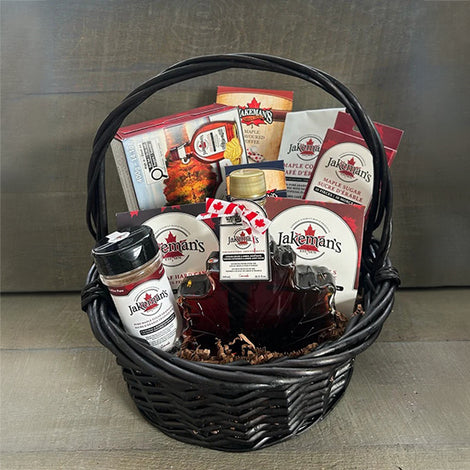 Black wicker gift basket with assorted maple-themed food items and labels.