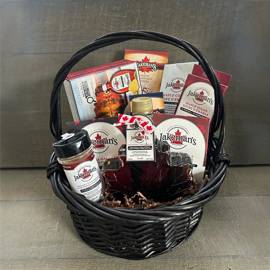 Black wicker gift basket with assorted maple-themed food items and labels.